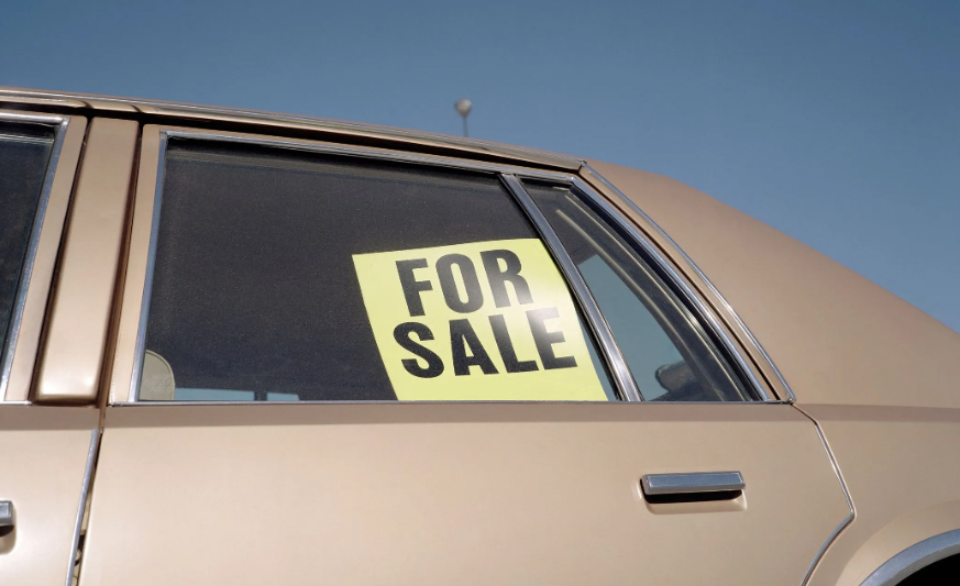 Car with a For Sale sign in the backseat window.