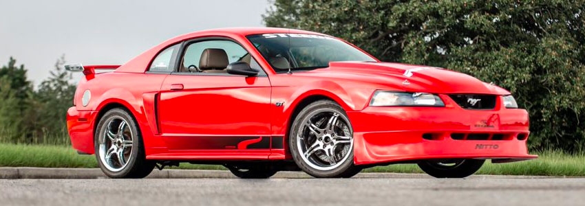 A parked red 2004 SN95 Ford Mustang