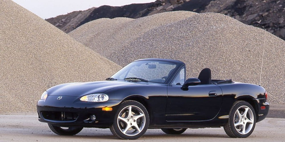 A parked dark blue 2001 Mazda MX-5 Miata