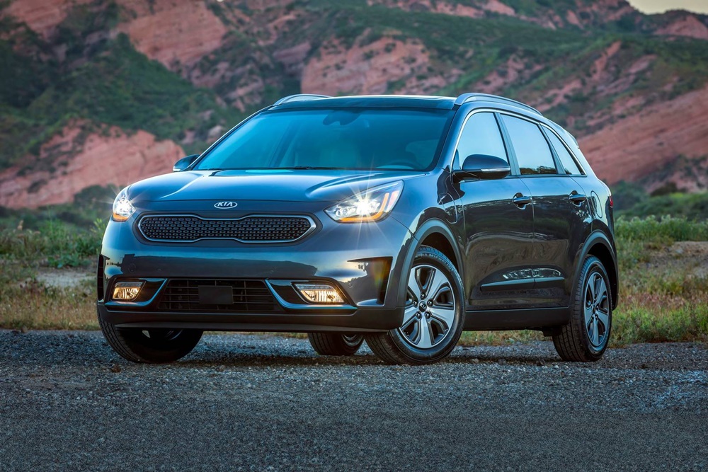 A parked dark grey 2019 Kia Niro Hybrid with headlights on