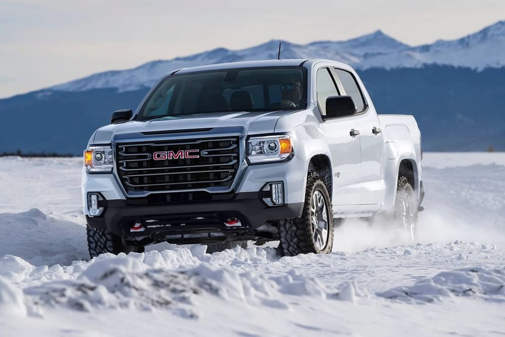 A white 2022 GMC Canyon crossing through snow