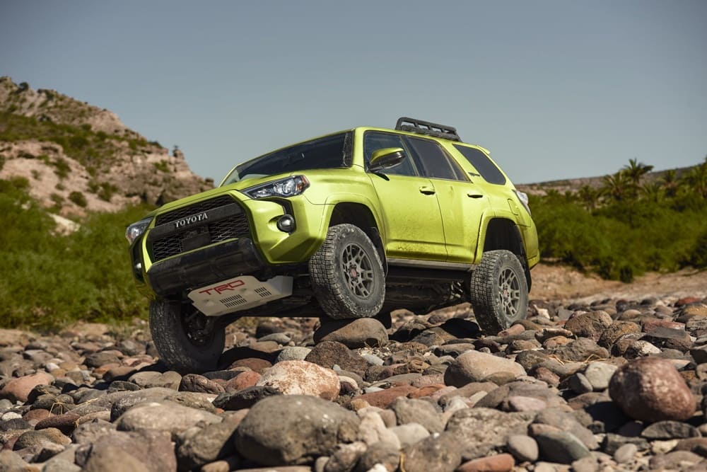 A yellow-green 2022 Toyota 4Runner going over rocky terrain