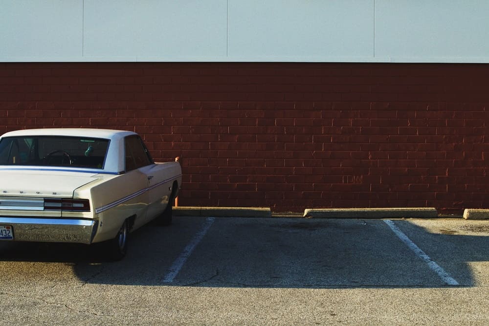 A white classic car in a parking lot