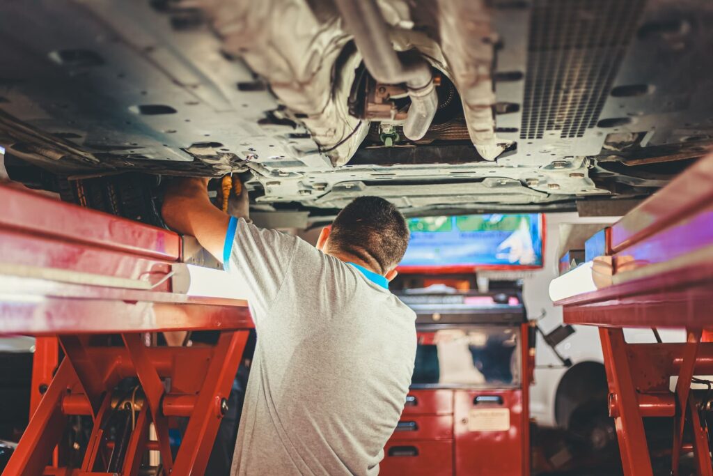 A mechanic working on the underside of a car