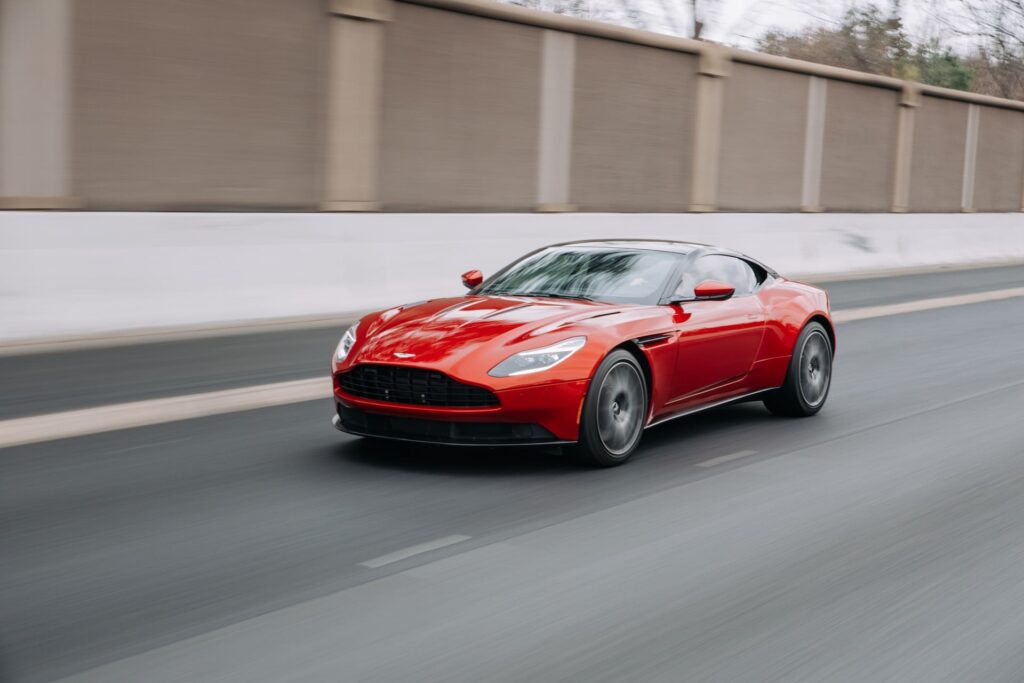 A red Aston Martin going down a street