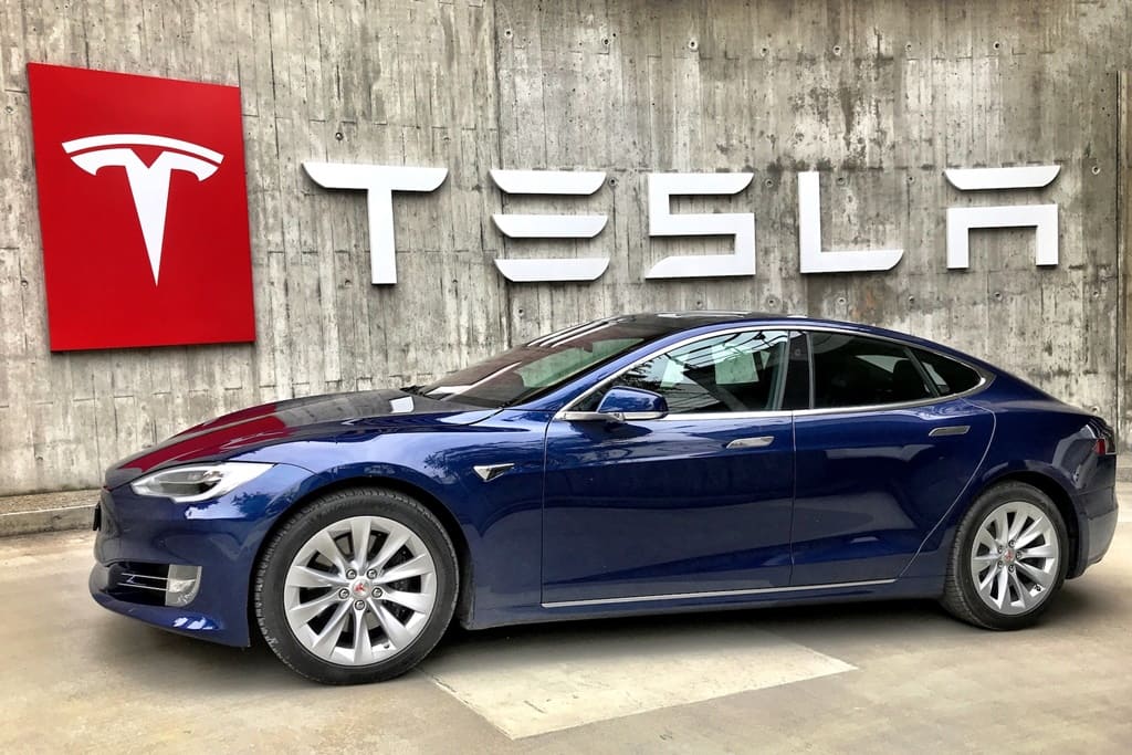A Tesla car parked in front of the company name